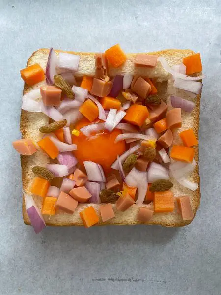 Step 5 Sprinkle carrot, onion, sausage raisins over the egg and toast